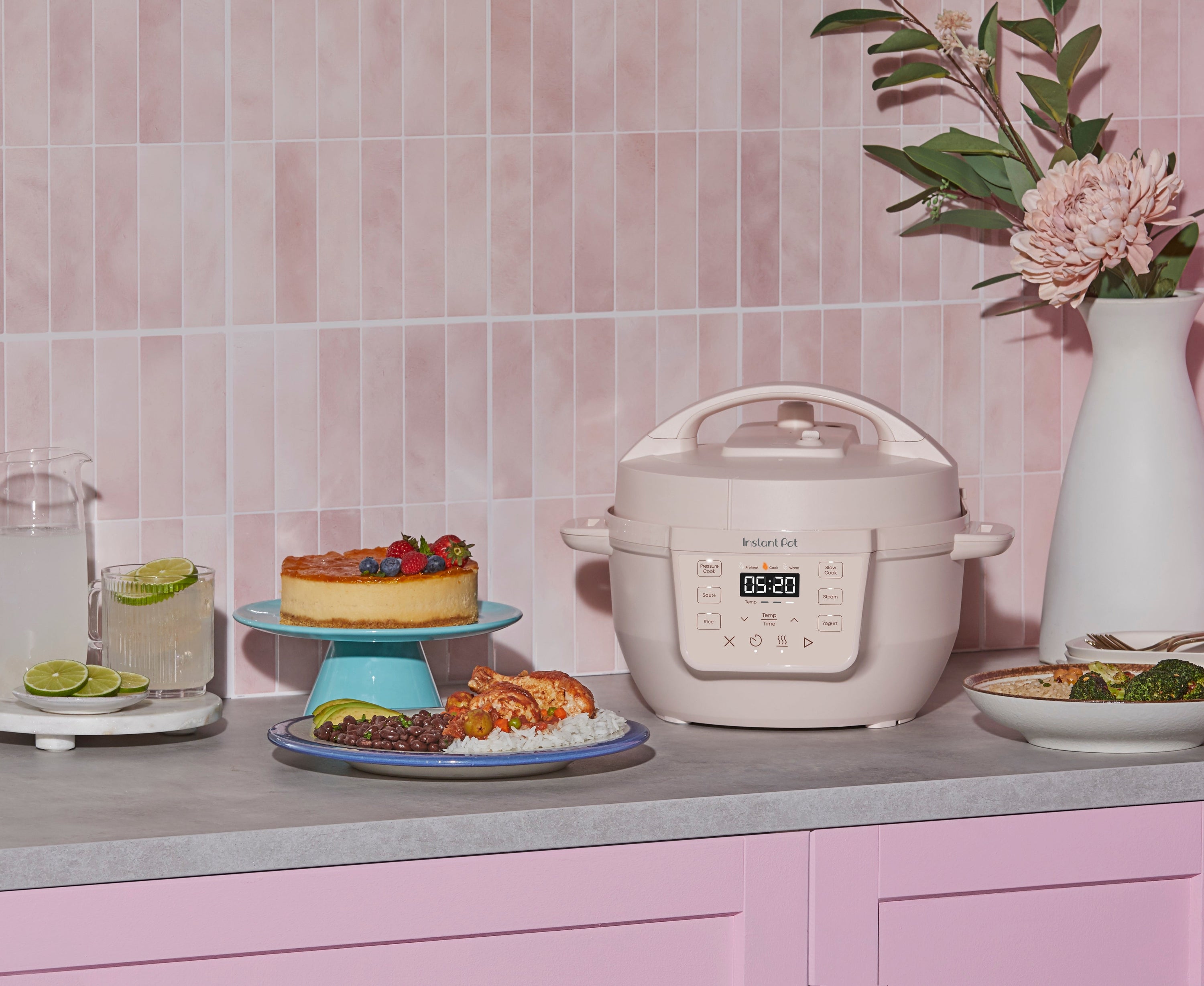 Instant Pot RIO Mini 4-Quart Multi-Cooker in Rosewater on pink kitchen counter with plated meal and dessert.