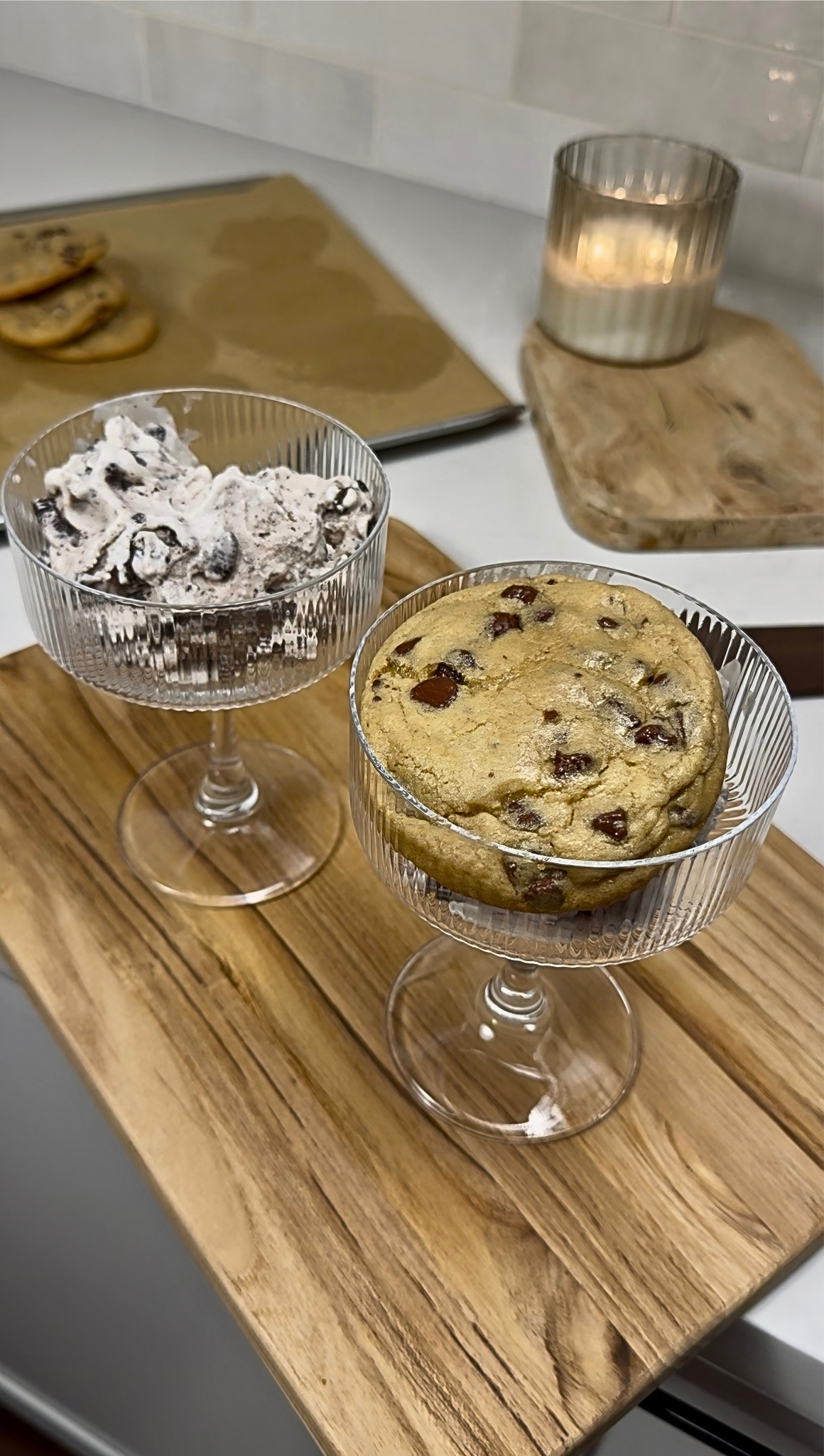 CHocolate chip cookie in a tall glass with ice cream in a similar tall glass on a kitchen counter