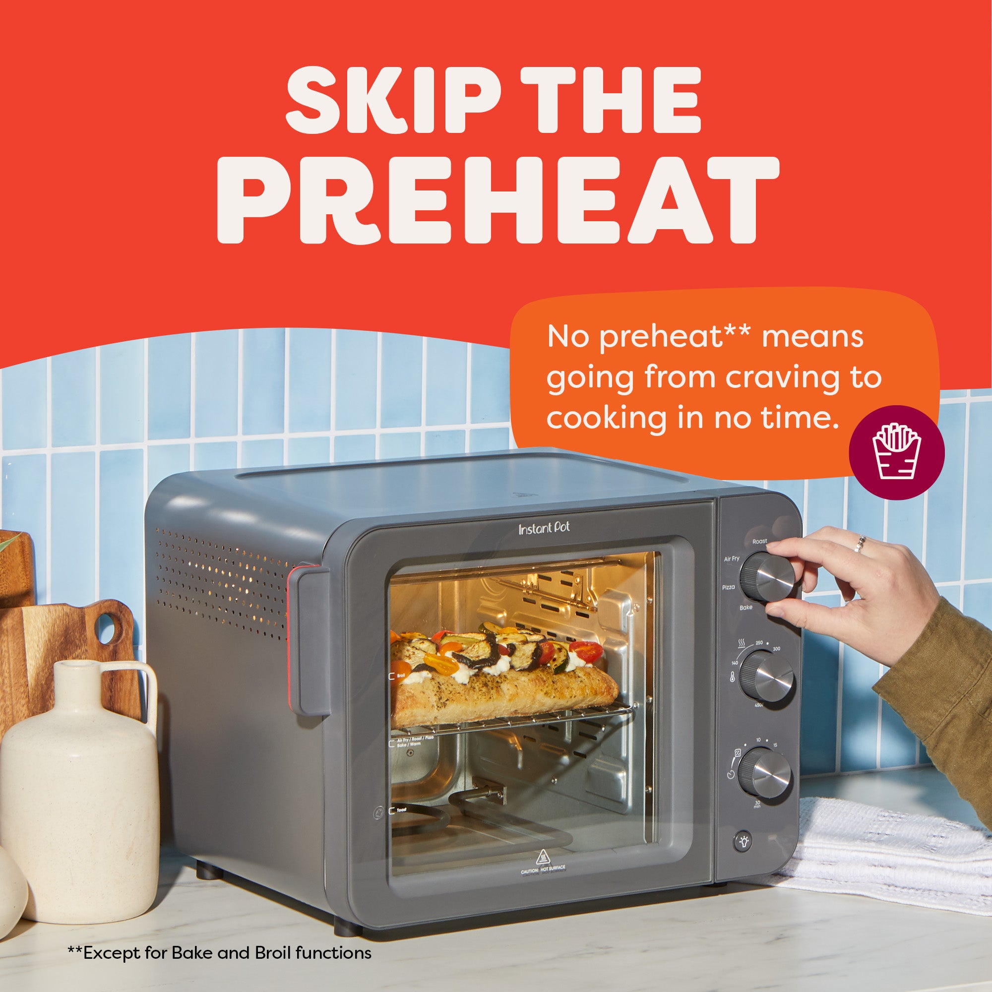 Gray toaster oven with a pizza inside, on a kitchen counter with a red background and text about skipping preheat.