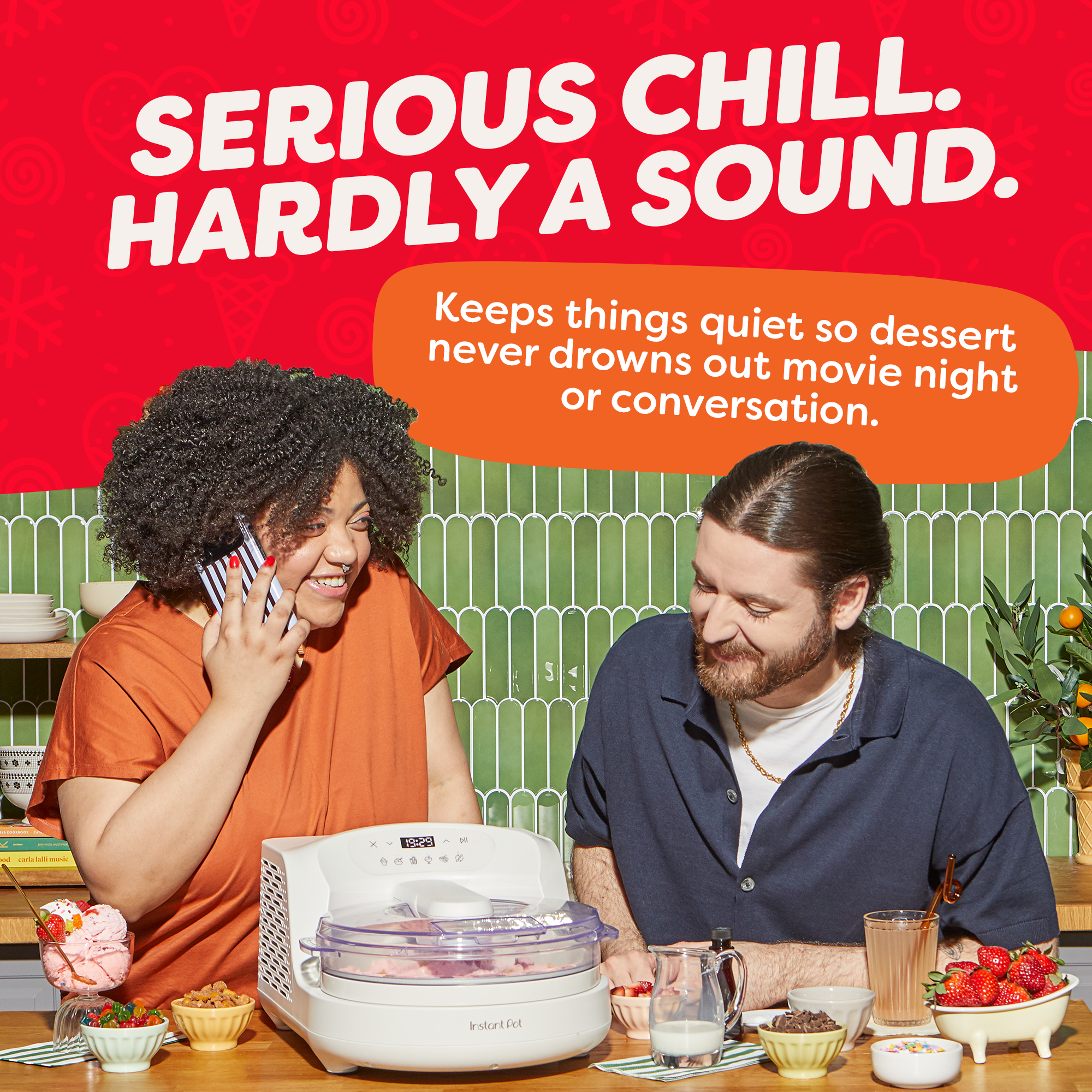 Two people sitting at a table with a InstantChill Ice Cream Maker, surrounded by a red background with text about low noise levels.